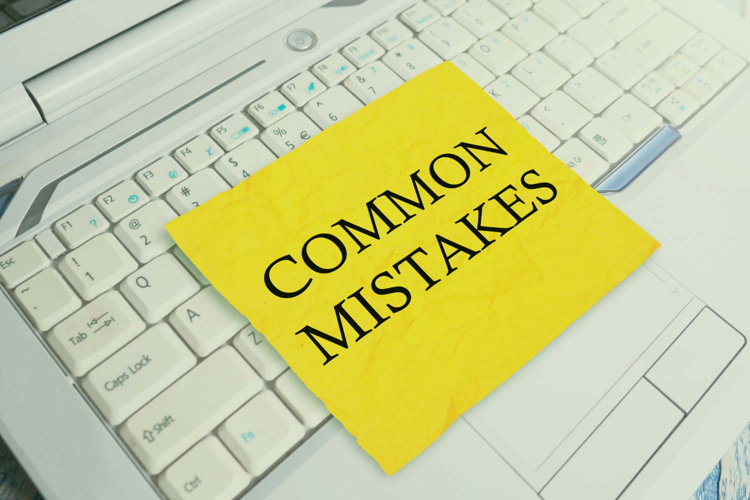 A sticky note that has “COMMON MISTAKES” written on it on the keyboard of a laptop.